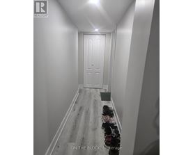 A hallway with a door at the end and a green bin on the floor.