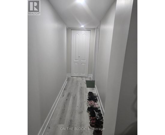 A hallway with a door at the end and a green bin on the floor.