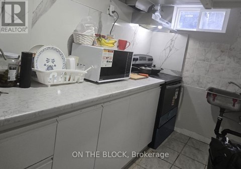 A kitchen counter with a white fridge and a black dishwasher.