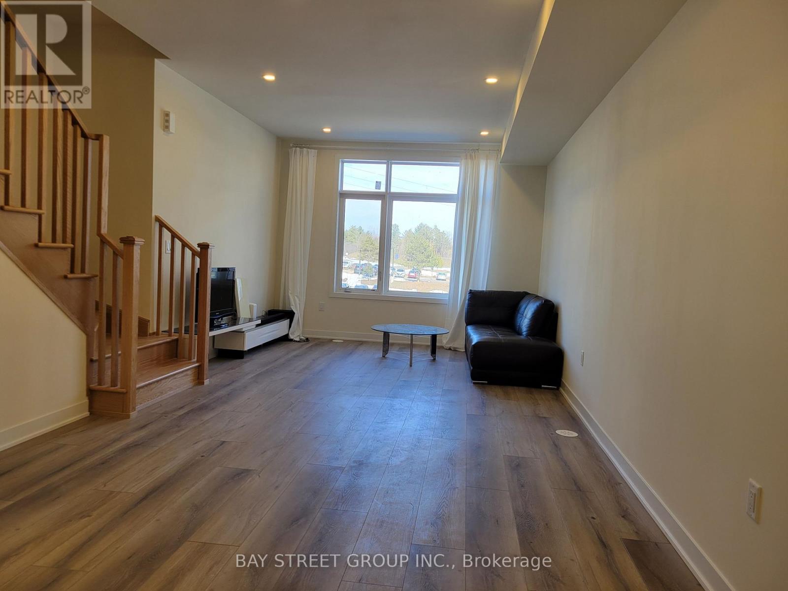 A spacious living room with a couch, chair, and a staircase.