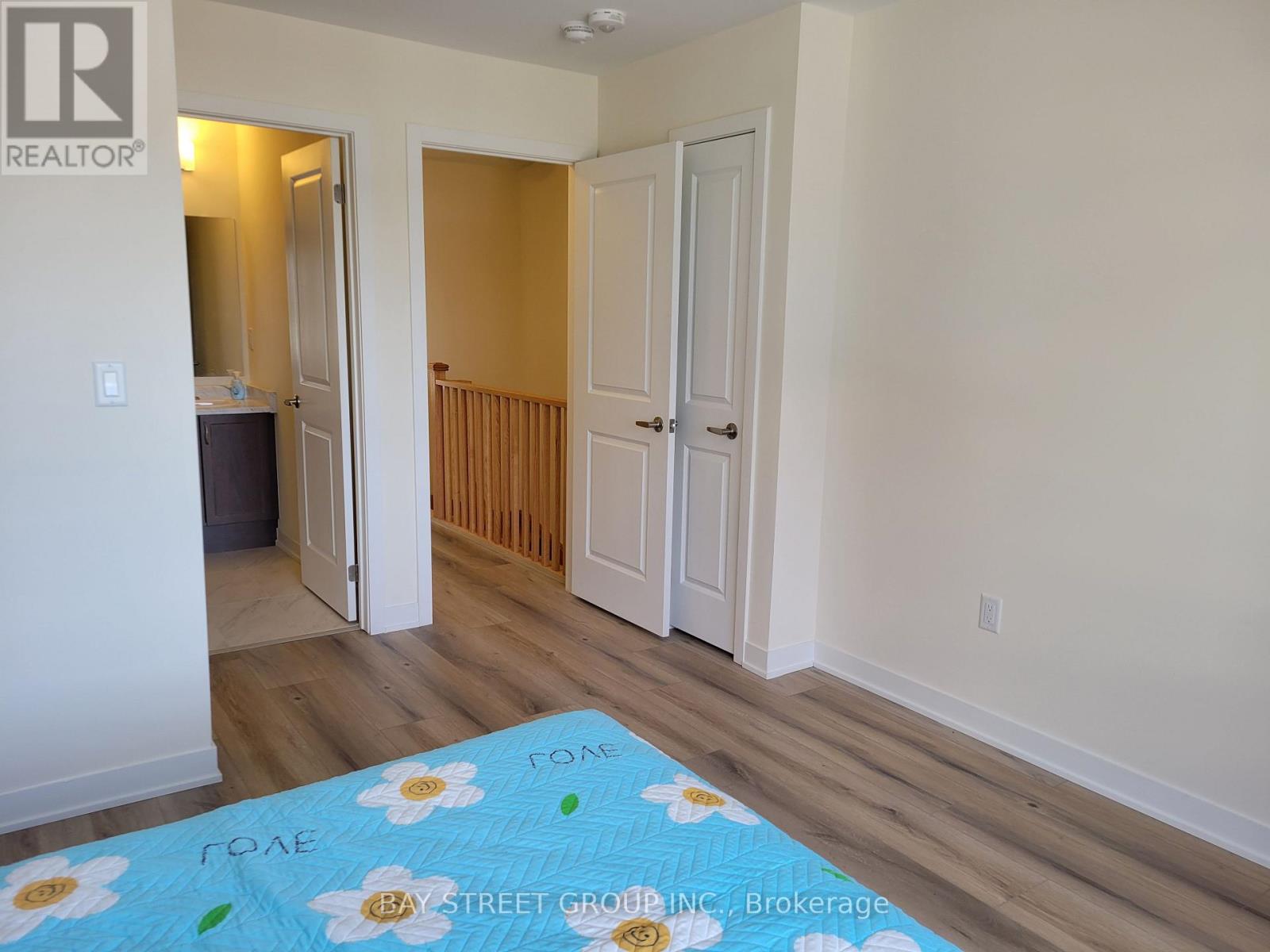 A bedroom with a bed and a brokerage sign on the wall.