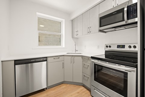 A modern kitchen with stainless steel appliances and wooden flooring.