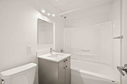 A white bathroom with a sink, mirror, and bathtub.