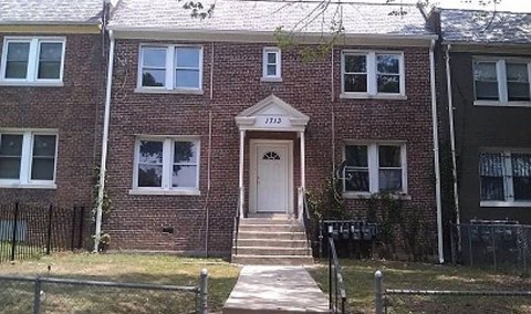 A red brick house with a white door and windows.