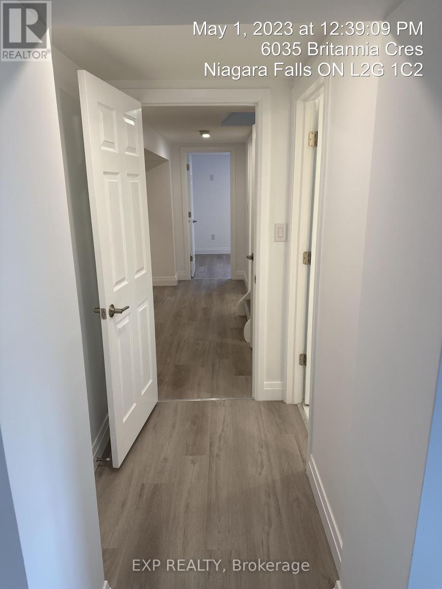 A hallway with white doors and grey flooring.