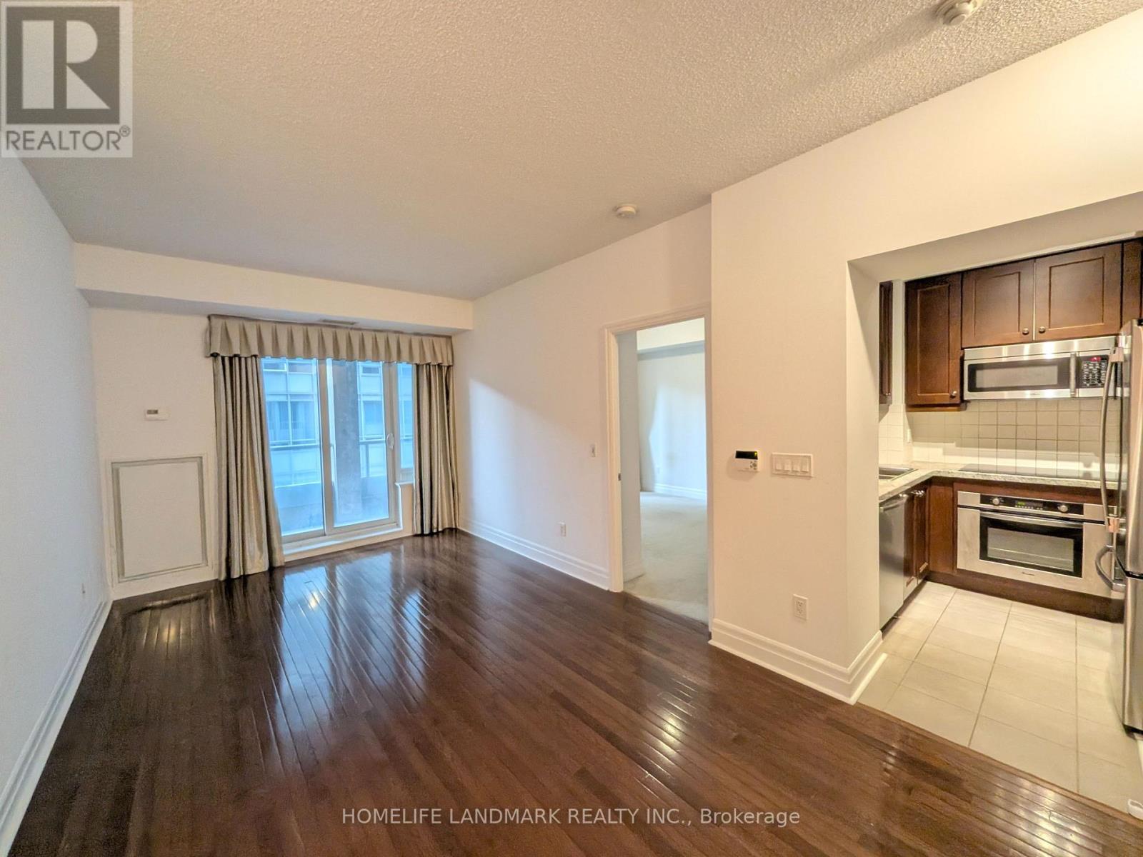A room with wooden flooring and a window with curtains.