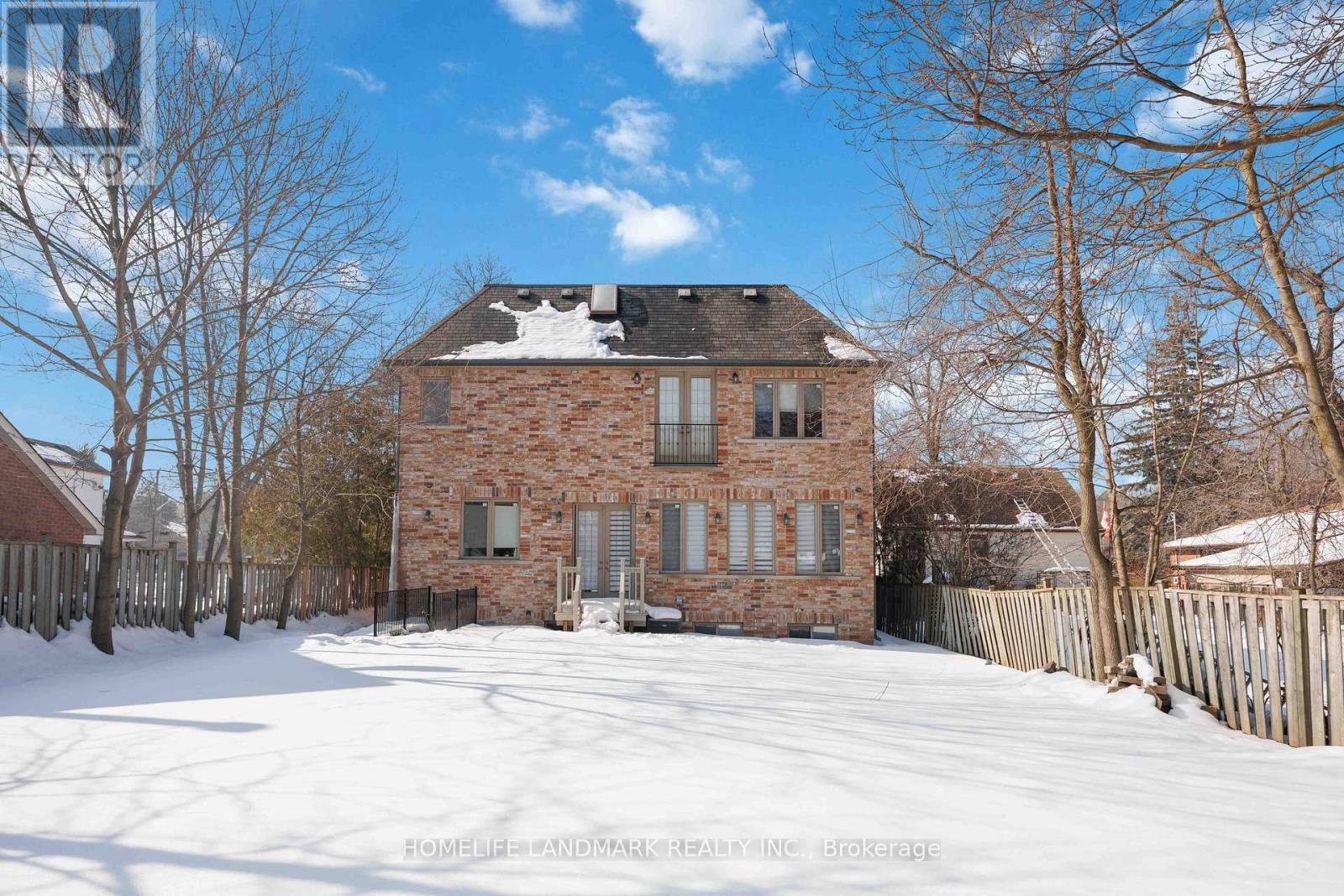 A brick house with snow on the ground and trees around it.