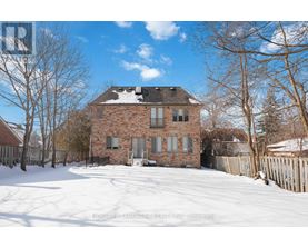 A brick house with snow on the ground and trees around it.