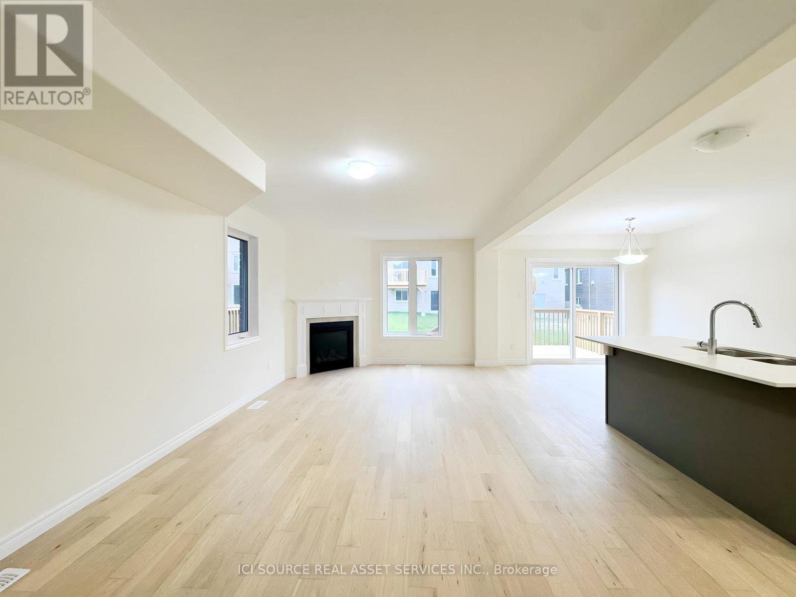 A spacious, empty room with wooden flooring and white walls.