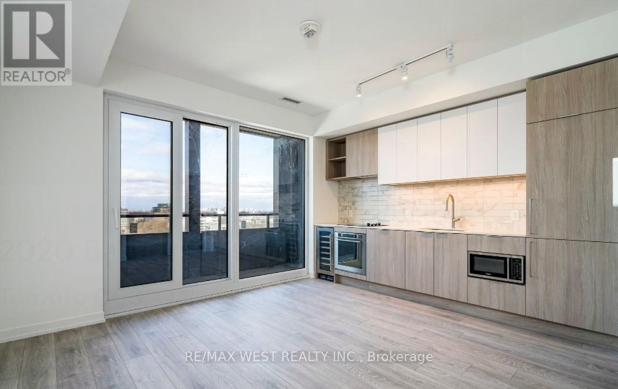 A spacious kitchen with wooden cabinets and a view of the city through the windows.