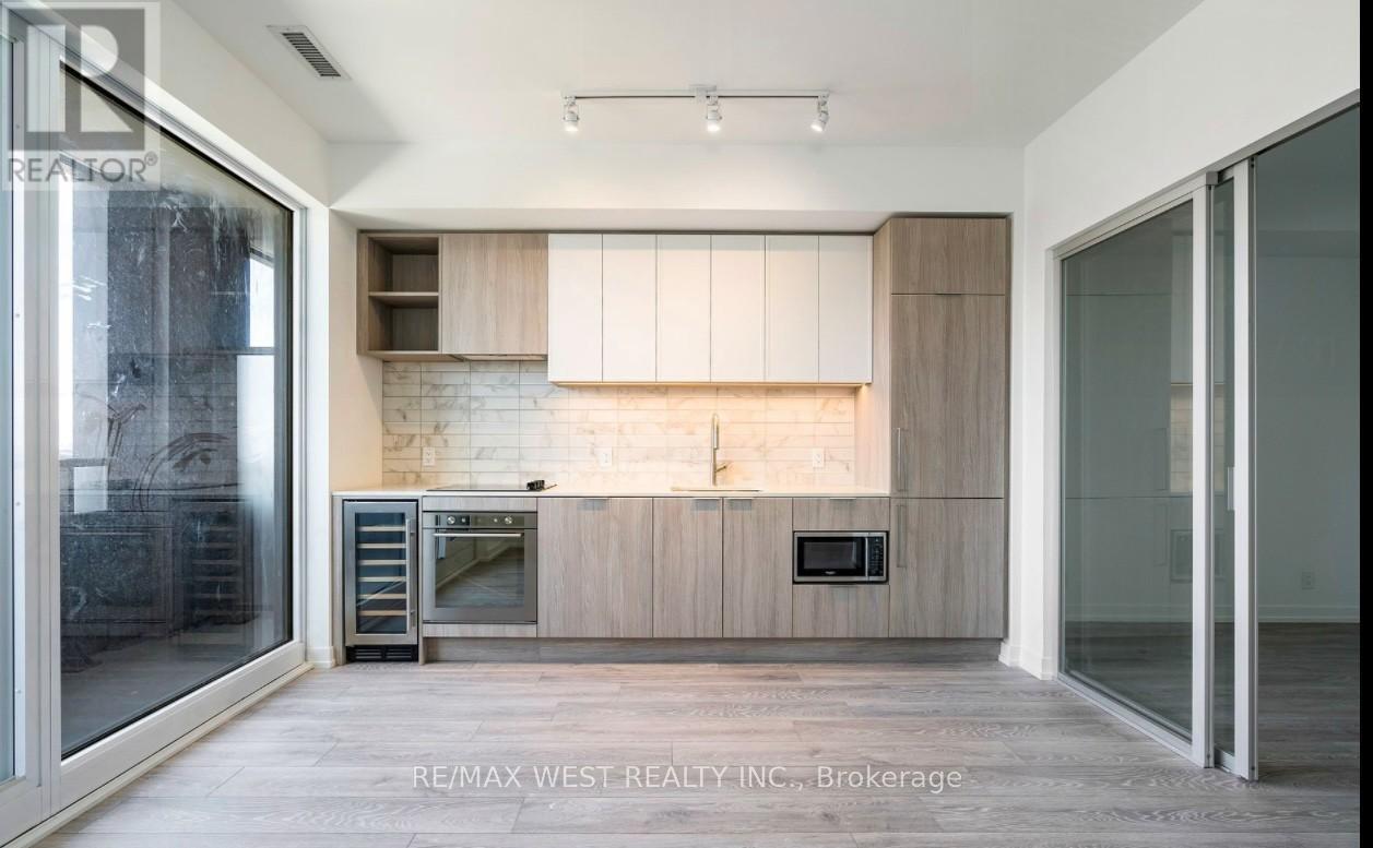 A modern kitchen with a refrigerator, oven, and microwave.