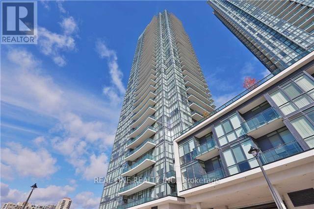 A tall building with a glass facade stands under a blue sky.