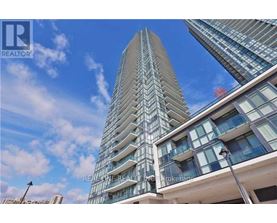 A tall building with a glass facade stands under a blue sky.