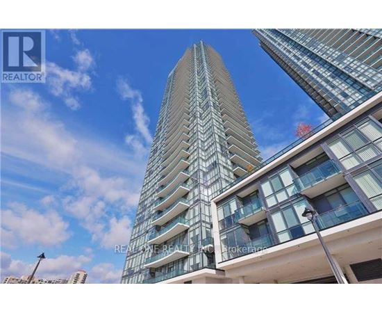 A tall building with a glass facade stands under a blue sky.