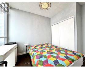 A bedroom with a bed covered in a multicolored quilt.