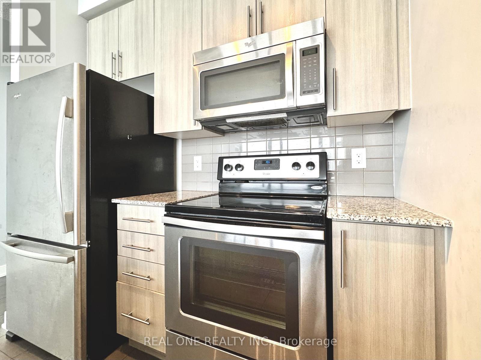 A black fridge and stove in a kitchen with wooden cabinets.