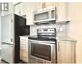 A black fridge and stove in a kitchen with wooden cabinets.