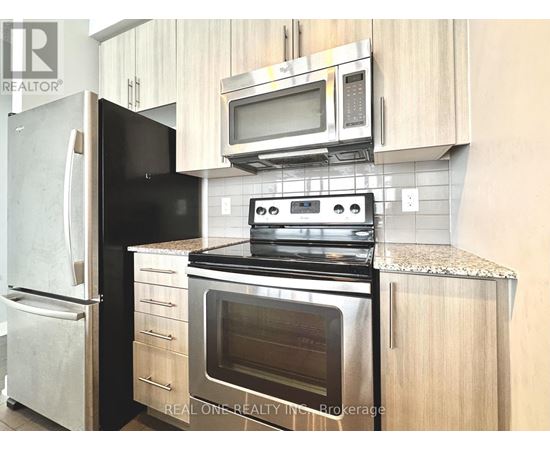A black fridge and stove in a kitchen with wooden cabinets.