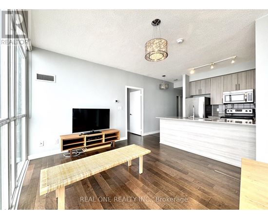 A modern living room with a wooden floor and a television on a wooden stand.