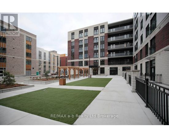 A view of a courtyard with a fence and a building in the background.