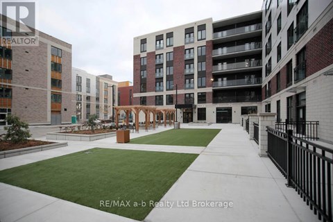 A view of a courtyard with a fence and a building in the background.