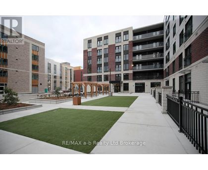 A view of a courtyard with a fence and a building in the background.