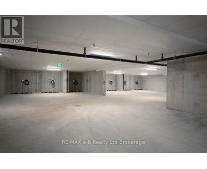 A large, empty warehouse space with concrete walls and floors, and a logo that reads "RE/MAX a-b Realty Ltd Brokerage" in the bottom right corner.