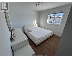 A bedroom with a bed, dresser, and window.