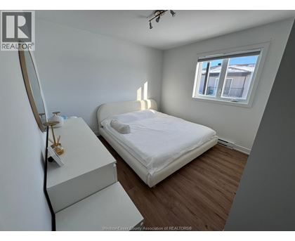 A bedroom with a bed, dresser, and window.