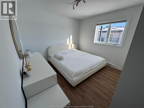 A bedroom with a bed, dresser, and window.