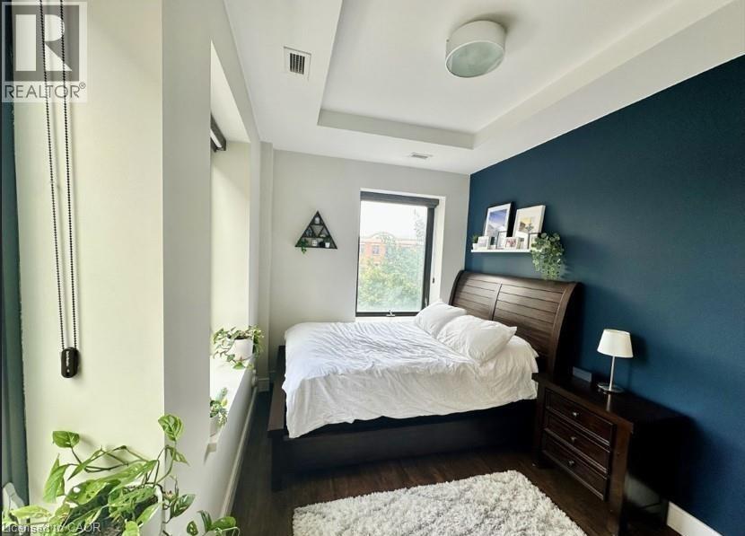 A bedroom with a bed, nightstand, and a plant.
