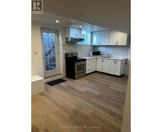 A kitchen with a refrigerator, stove, and cabinets.