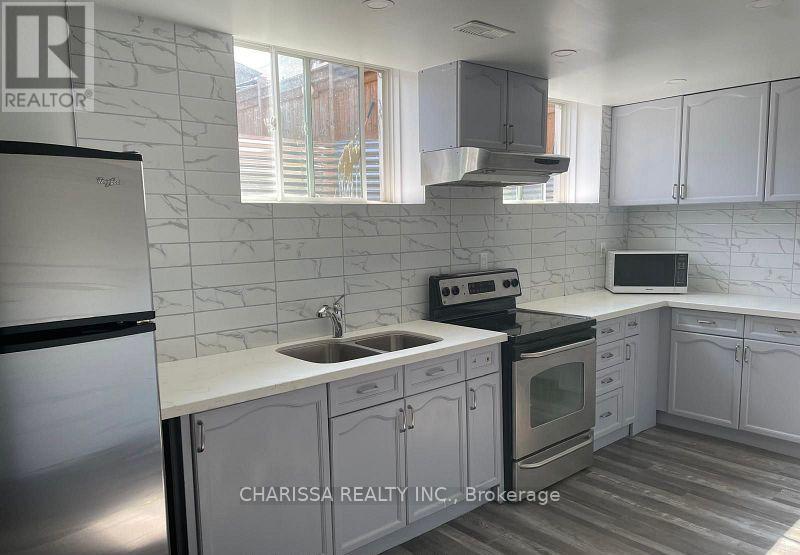 A kitchen with a refrigerator, sink, stove, and cabinets.
