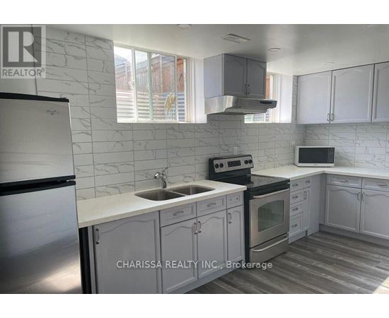 A kitchen with a refrigerator, sink, stove, and cabinets.
