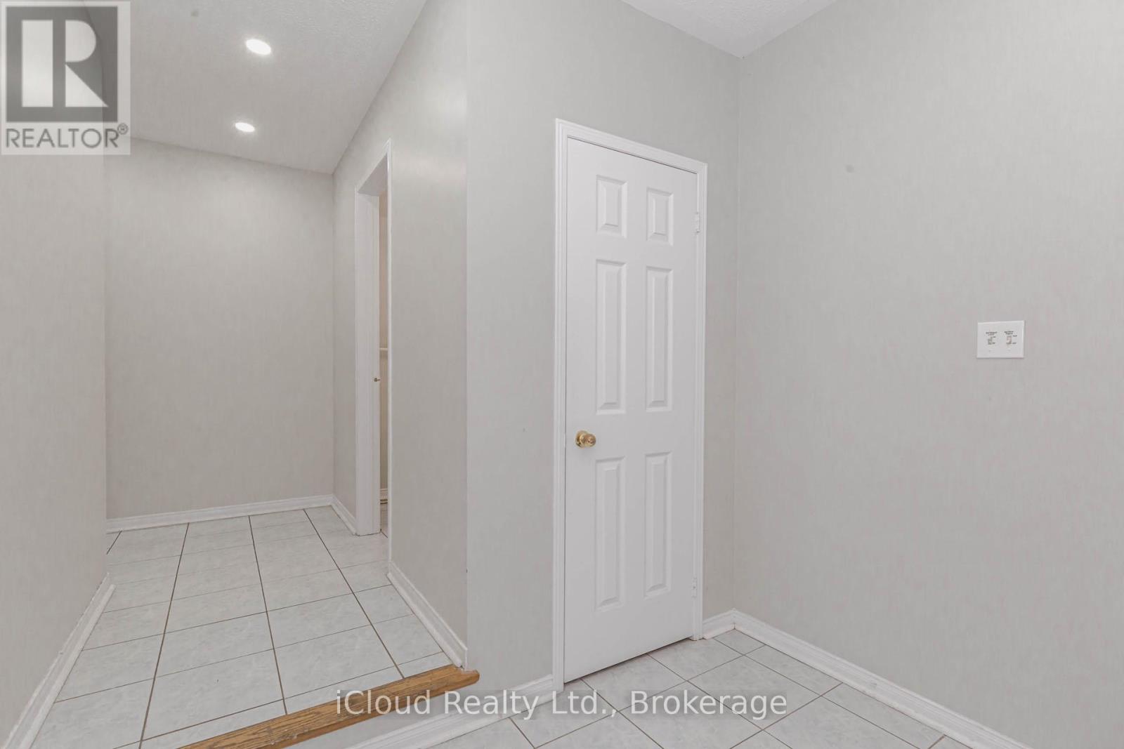 A white door is in a room with white walls and tile flooring.