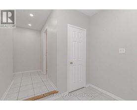 A white door is in a room with white walls and tile flooring.