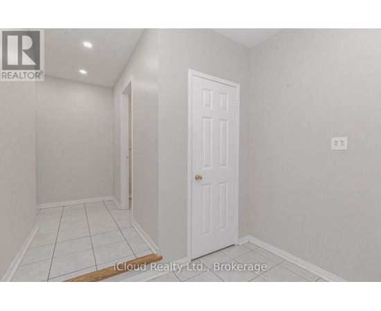 A white door is in a room with white walls and tile flooring.