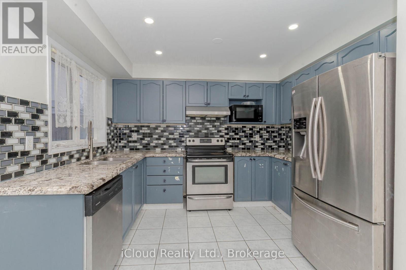 A kitchen with a stainless steel refrigerator and a checkered backsplash.
