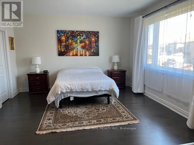 A bedroom with a large bed and a painting on the wall.