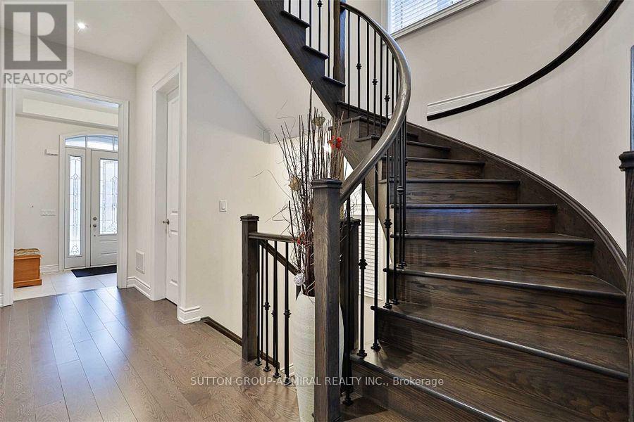 A wooden staircase with a metal railing and a vase of flowers on top.