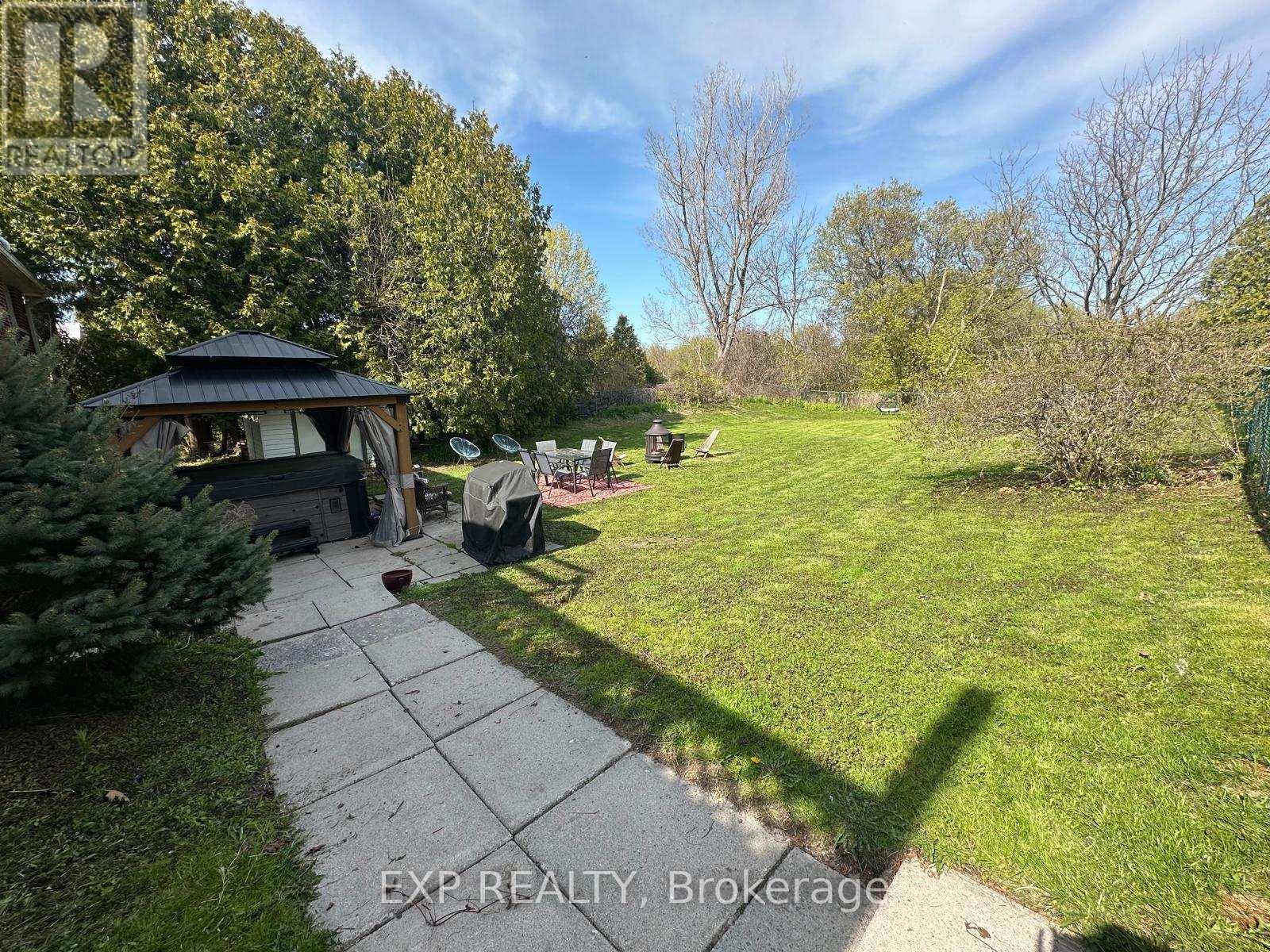 A backyard with a gazebo and a concrete walkway.