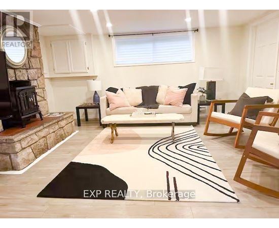 A living room with a white couch, a stone fireplace, and a rug with black lines.
