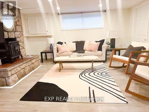 A living room with a white couch, a stone fireplace, and a rug with black lines.
