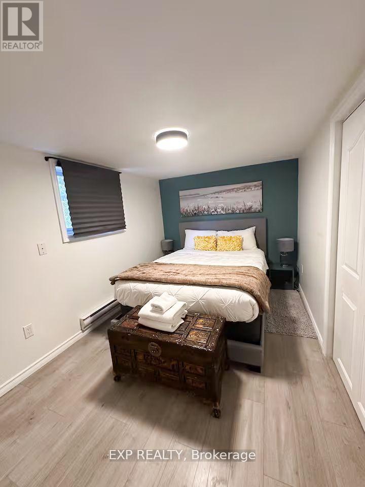A bedroom with a bed, nightstand, and window with blinds.
