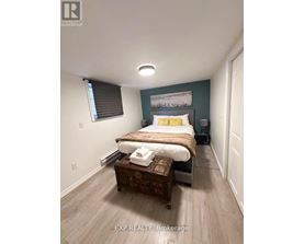 A bedroom with a bed, nightstand, and window with blinds.