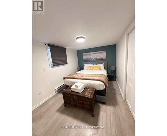 A bedroom with a bed, nightstand, and window with blinds.