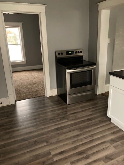 A modern kitchen with a stainless steel oven and wooden flooring.