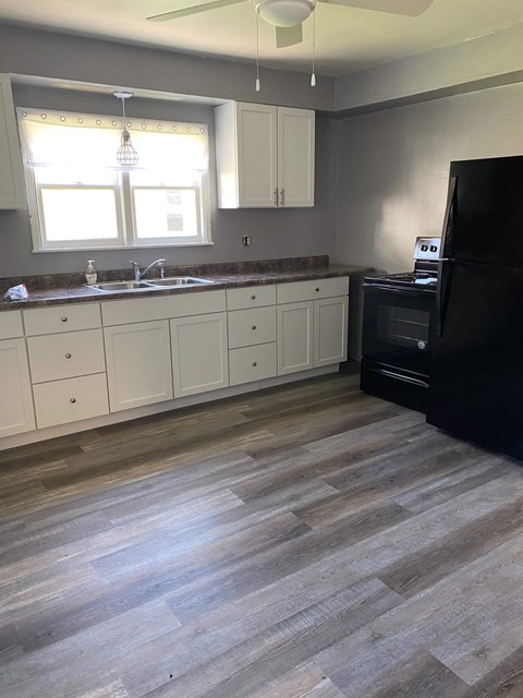 A kitchen with a black fridge and white cabinets.