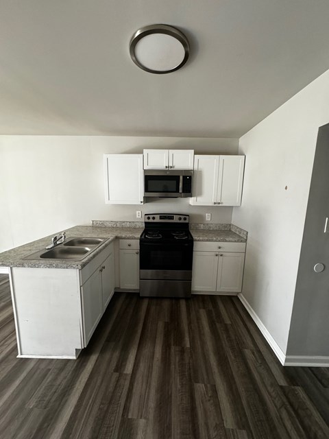 A kitchen with white cabinets and a granite countertop.