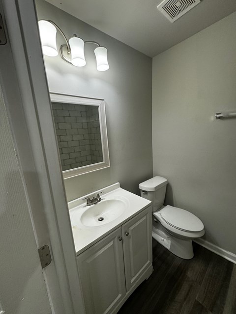 A small bathroom with a toilet, sink, and mirror.